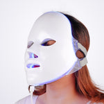 Woman wearing LED photon therapy face mask during home skin treatment